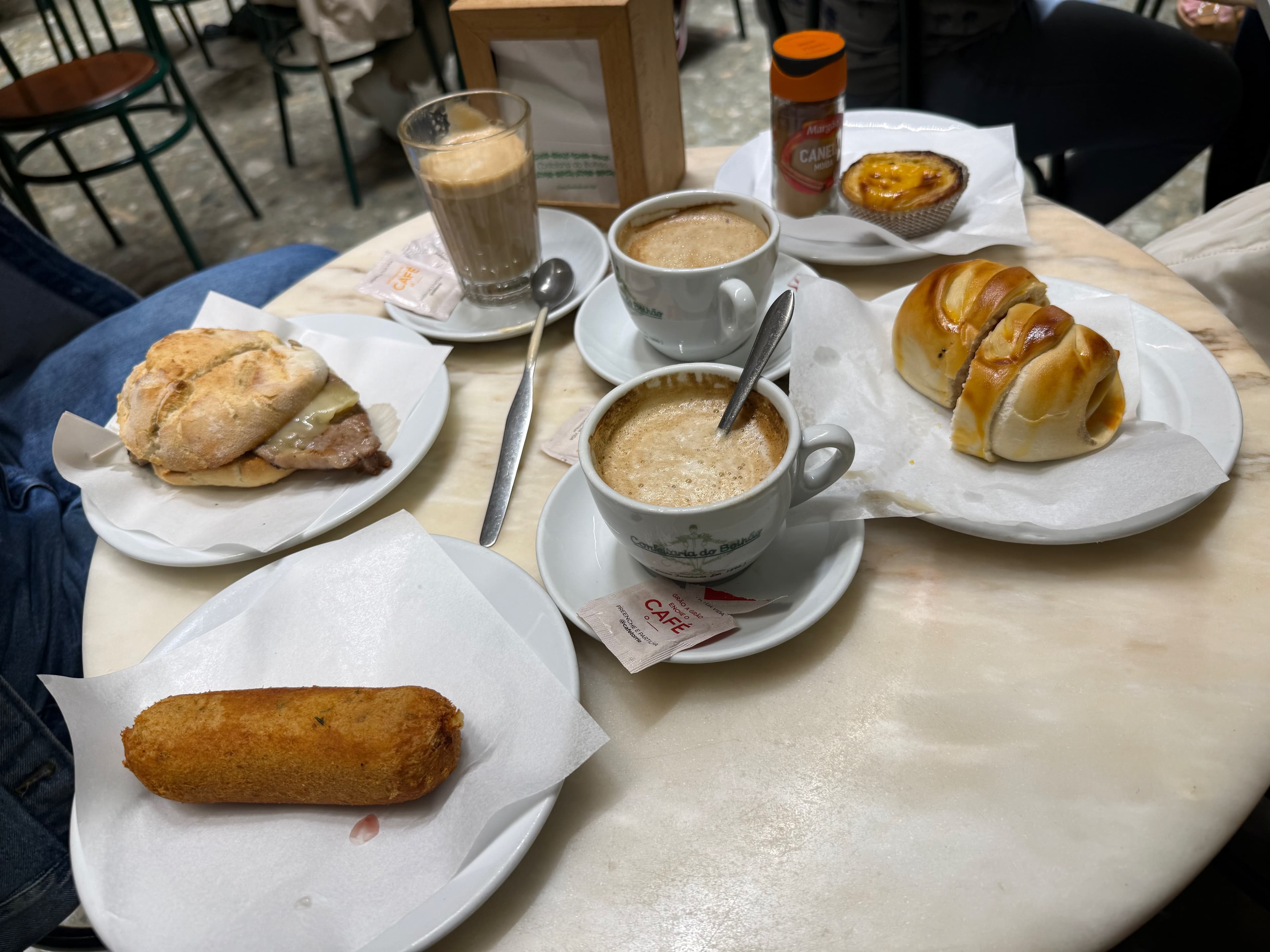 A rich brunch spread at Confeitaria do Bolhão, featuring local pastries, savory rolls, and aromatic Portuguese coffee.