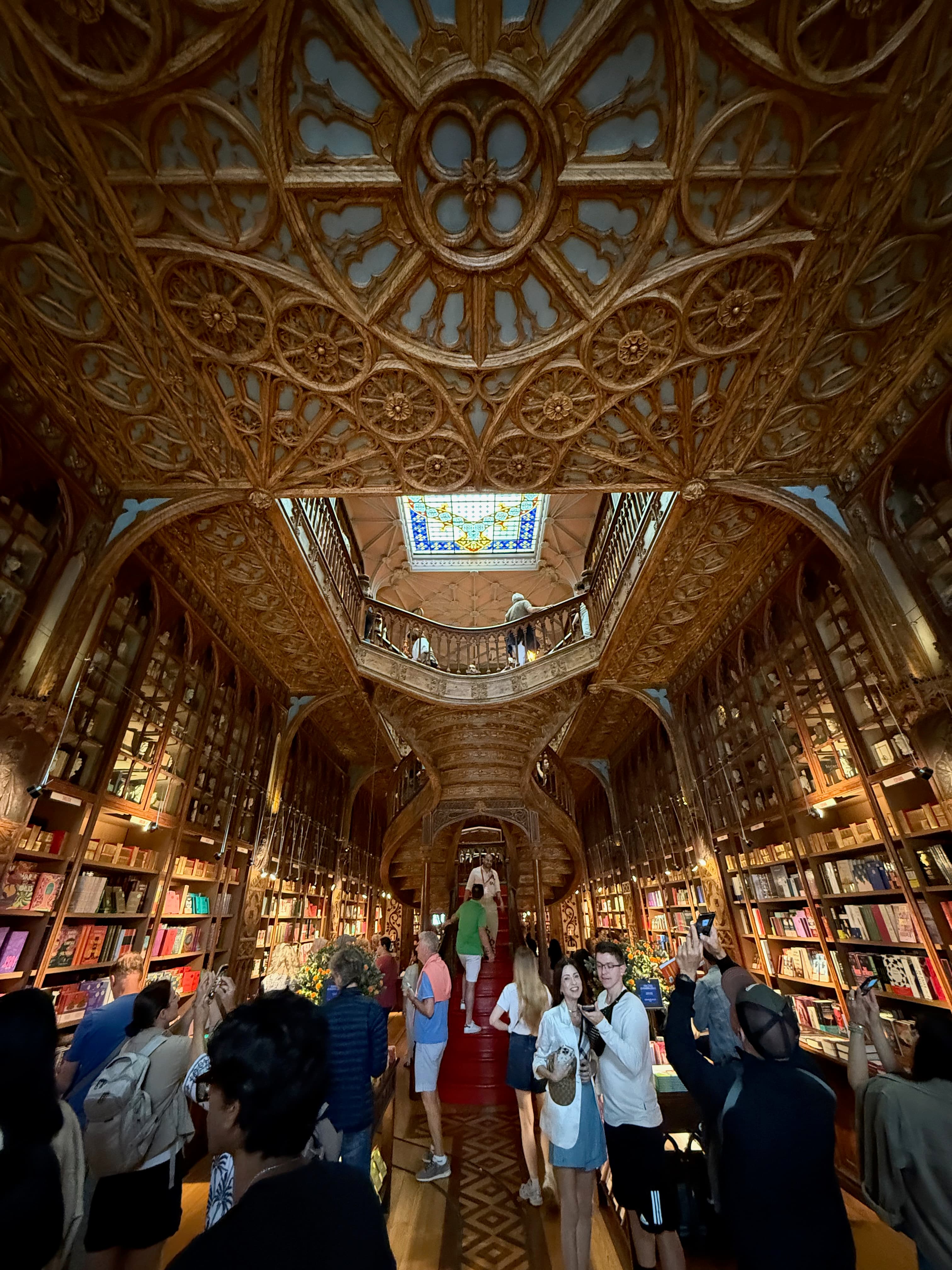 Looking up at the magical, crowded interior and the famous crimson staircase of Livraria Lello.