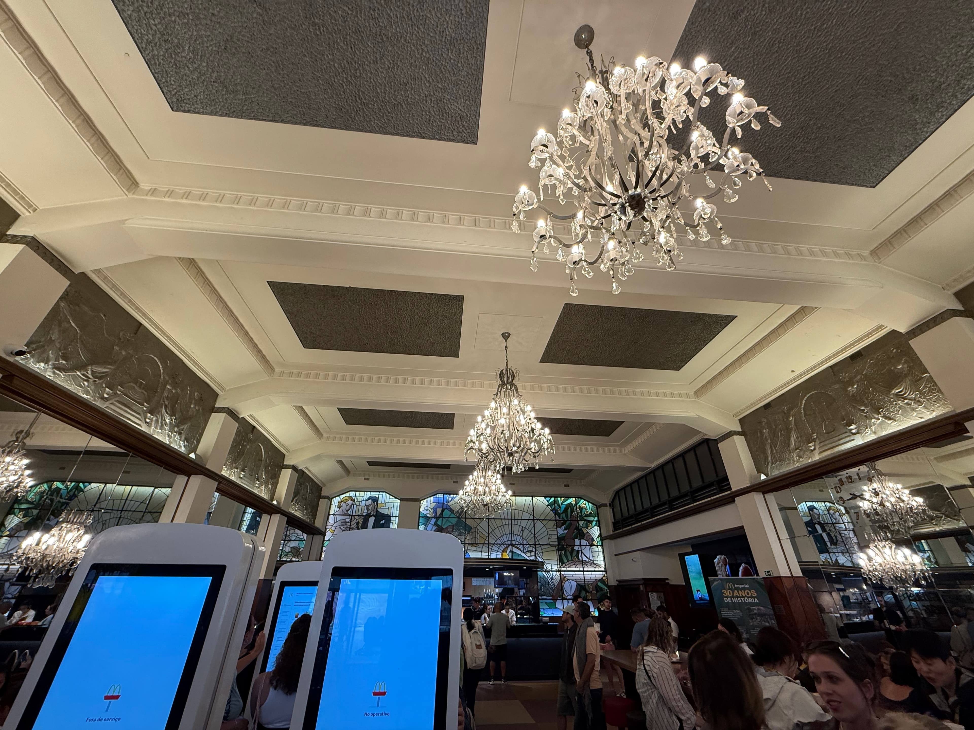Looking up at the elegant crystal chandeliers and detailed art deco plasterwork on the ceiling.