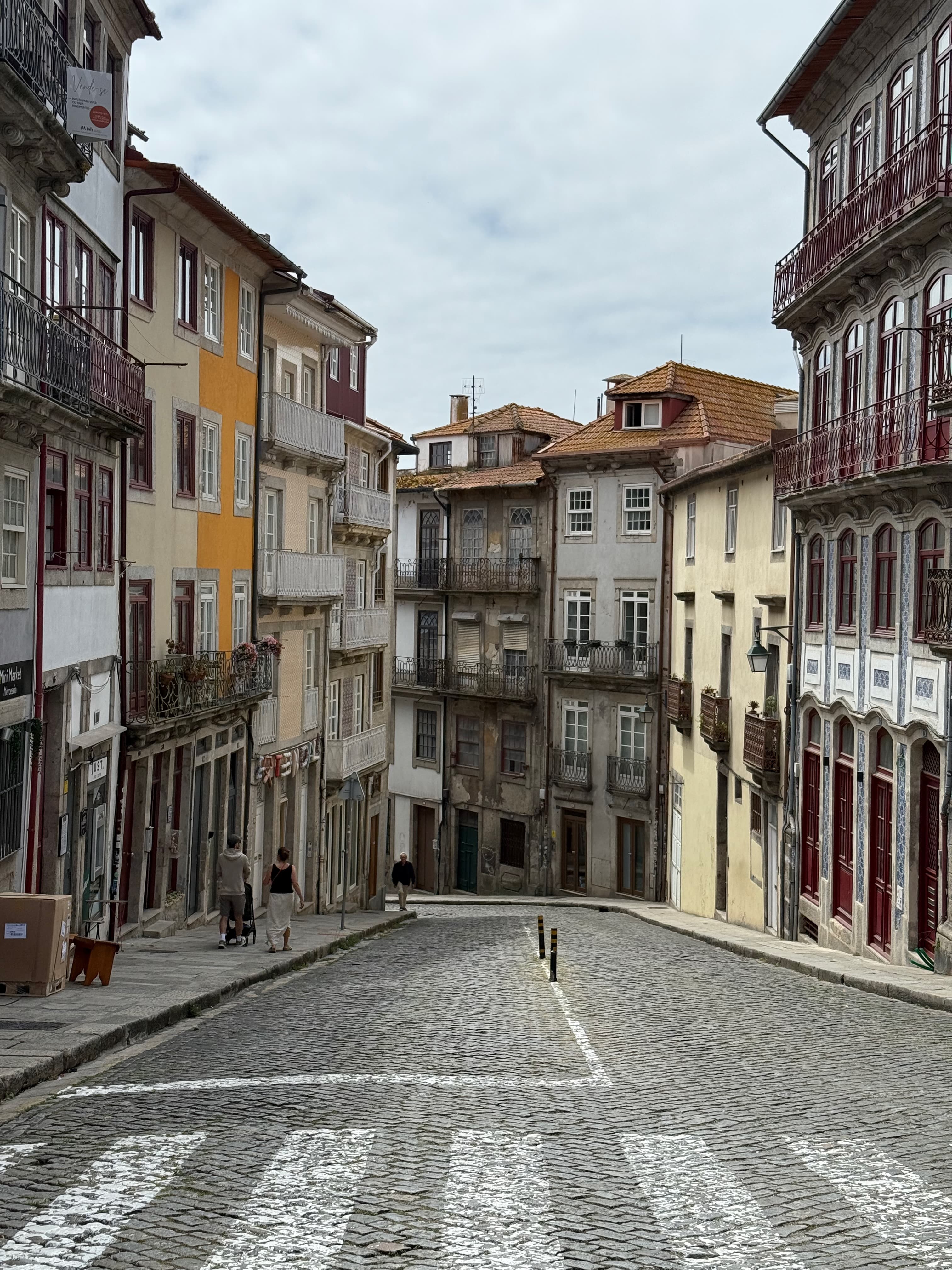 Walking down a quiet, scenic cobblestone street surrounded by traditional Portuguese architecture.