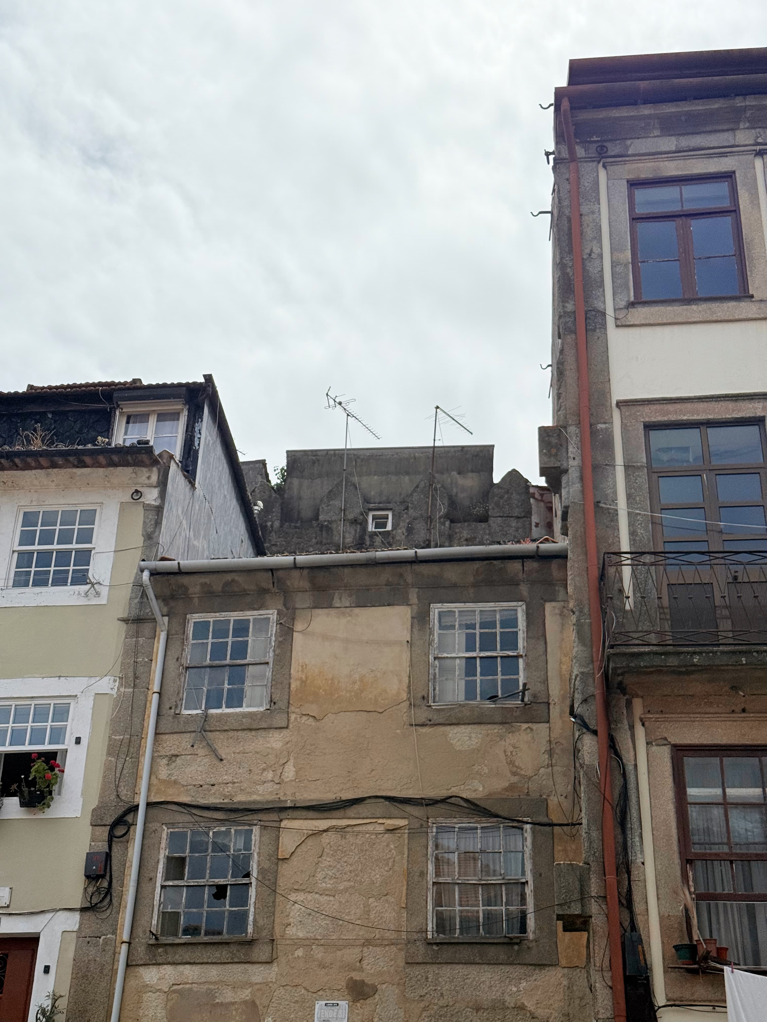 Historic stone ruins peeking out from the rooftop of a residential building.
