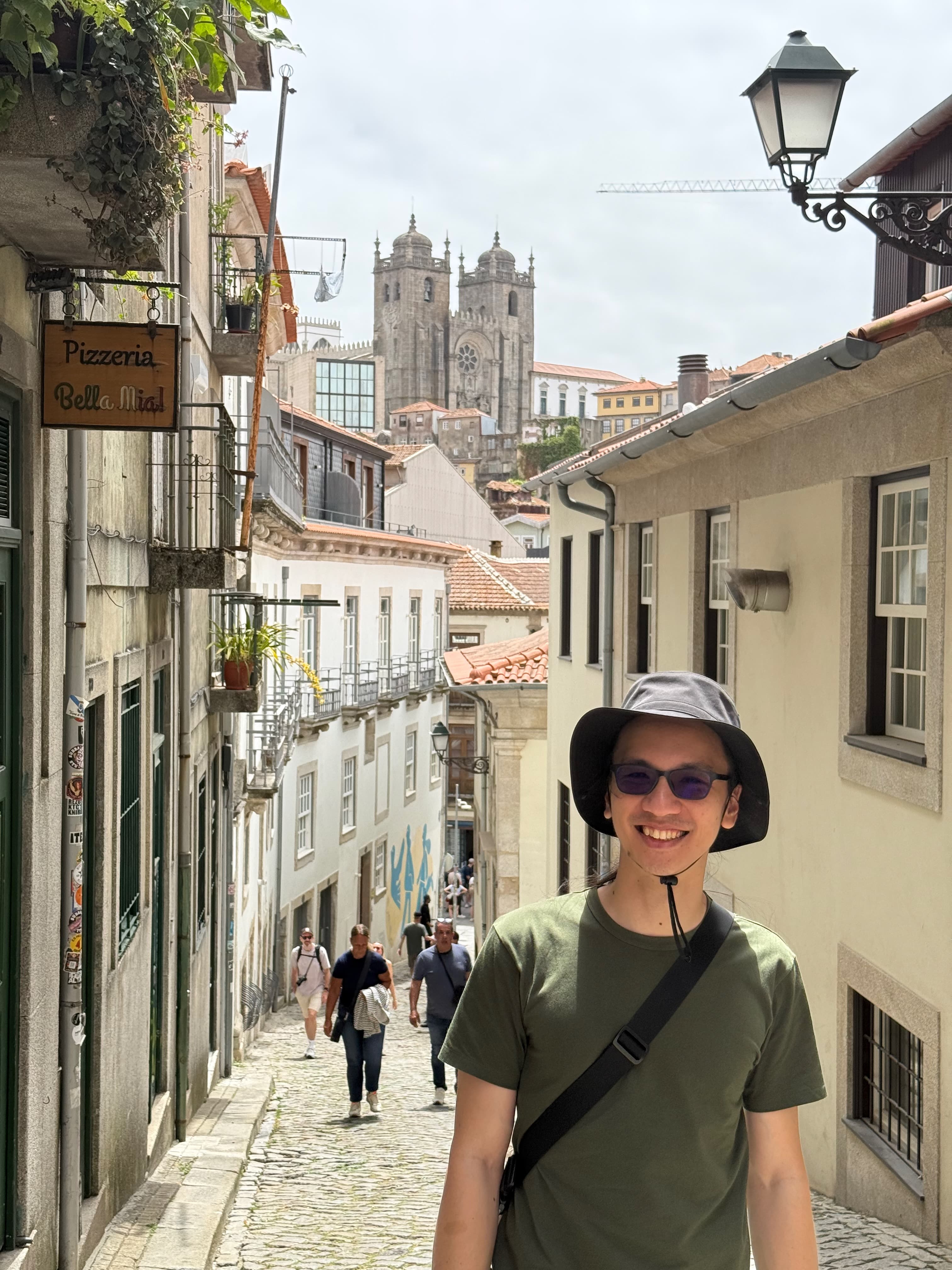 Posing on the steep stone path of Rua do Ferraz with the historic cathedral standing tall behind.